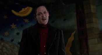 Movie still from “The Addams Family” (1991), directed by Barry Sonnenfeld – A man in a black jacket and red shirt; Medium shot, Low angle