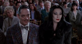 Movie still from “The Addams Family” (1991), directed by Barry Sonnenfeld – A man and a woman dressed as gomez and morticia addams; Medium shot, Low angle