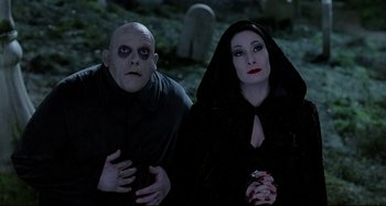 Movie still from “The Addams Family” (1991), directed by Barry Sonnenfeld – A man and a woman dressed as vampires in a cemetery; Medium shot, Low angle