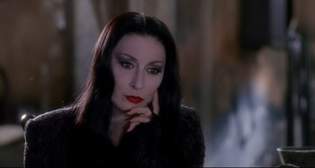 Movie still from “The Addams Family” (1991), directed by Barry Sonnenfeld – A person with long black hair; Close Up shot, Over the shoulder angle