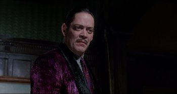 Movie still from “The Addams Family” (1991), directed by Barry Sonnenfeld – A person wearing a suit and tie; Close Up shot, Low angle