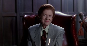Movie still from “The Addams Family” (1991), directed by Barry Sonnenfeld – An older woman wearing a suit and tie; Medium shot, Over the shoulder angle