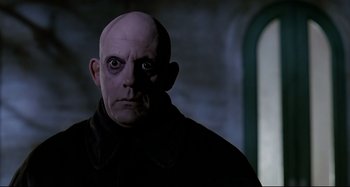 Movie still from “The Addams Family” (1991), directed by Barry Sonnenfeld – A man with a bald head wearing a black jacket; Close Up shot, Low angle