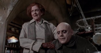 Movie still from “The Addams Family” (1991), directed by Barry Sonnenfeld – An older woman standing next to an older man; Medium shot, Low angle