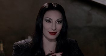 Movie still from “The Addams Family” (1991), directed by Barry Sonnenfeld – A person with long black hair; Close Up shot, Over the shoulder angle