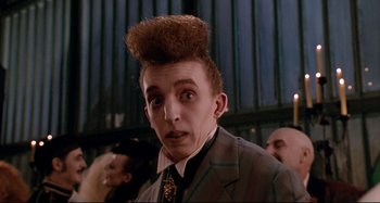 Movie still from “The Addams Family” (1991), directed by Barry Sonnenfeld – A person wearing a suit and tie; Close Up shot, Low angle