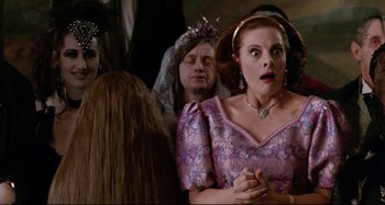 Movie still from “The Addams Family” (1991), directed by Barry Sonnenfeld – A woman in a purple dress and a man in a black suit; Close Up shot, Over the shoulder angle