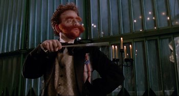 Movie still from “The Addams Family” (1991), directed by Barry Sonnenfeld – A man in a suit and tie holding a sword; Medium shot, Low angle