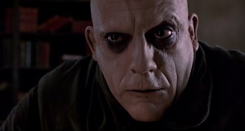 Movie still from “The Addams Family” (1991), directed by Barry Sonnenfeld – A man's face with a creepy look; Close Up shot, Low angle