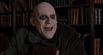 Movie still from “The Addams Family” (1991), directed by Barry Sonnenfeld – A man's face with a book in front of him; Close Up shot, Low angle