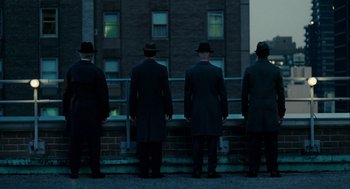 Movie still from “The Adjustment Bureau” (2011), directed by George Nolfi – A group of men standing next to each other on the side of a building; Wide shot, Low angle