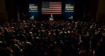 Movie still from “The Adjustment Bureau” (2011), directed by George Nolfi – A crowd of people sitting and standing in front of an american flag; Extreme Wide shot, Overhead angle