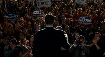 Movie still from “The Adjustment Bureau” (2011), directed by George Nolfi – A crowd of people holding up signs in front of a man in a suit; Wide shot, High angle
