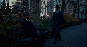 Movie still from “The Adjustment Bureau” (2011), directed by George Nolfi – Two men in suits and hats sitting on a park bench; Wide shot, Over the shoulder angle