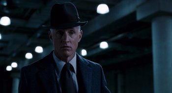 Movie still from “The Adjustment Bureau” (2011), directed by George Nolfi – A man wearing a suit and a hat in a dark room; Close Up shot, Low angle
