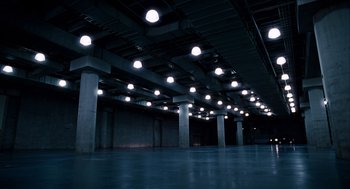 Movie still from “The Adjustment Bureau” (2011), directed by George Nolfi – An empty warehouse with lights on the ceiling; Extreme Wide shot, High angle