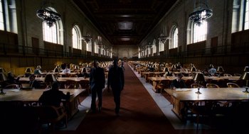 Movie still from “The Adjustment Bureau” (2011), directed by George Nolfi – Two men are walking through a library filled with tables; Extreme Wide shot, High angle