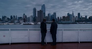 Movie still from “The Adjustment Bureau” (2011), directed by George Nolfi – Two men standing on the deck of a boat looking out at a city; Extreme Wide shot, High angle