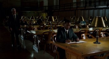 Movie still from “The Adjustment Bureau” (2011), directed by George Nolfi – A man sitting at a table writing on a piece of paper; Wide shot, High angle