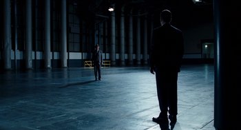 Movie still from “The Adjustment Bureau” (2011), directed by George Nolfi – Two men in suits are standing in an empty warehouse; Wide shot, High angle
