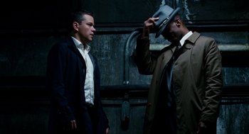 Movie still from “The Adjustment Bureau” (2011), directed by George Nolfi – Two men standing next to each other wearing suits and hats; Medium shot, Low angle