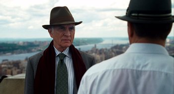 Movie still from “The Adjustment Bureau” (2011), directed by George Nolfi – A man wearing a hat and a tie talking to another man wearing a hat and a tie; Close Up shot, Over the shoulder angle