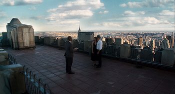 Movie still from “The Adjustment Bureau” (2011), directed by George Nolfi – A man and a woman standing next to each other on top of a building; Extreme Wide shot, High angle