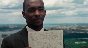 Movie still from “The Adjustment Bureau” (2011), directed by George Nolfi – A man in a business suit holding up a drawing; Close Up shot, High angle