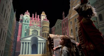 Movie still from “The Adventures of Baron Munchausen” (1988), directed by Terry Gilliam – A girl holding a painting in front of a castle; Extreme Wide shot, Over the shoulder angle