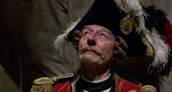 Movie still from “The Adventures of Baron Munchausen” (1988), directed by Terry Gilliam – An old man in a uniform and a hat with feathers; Close Up shot, Low angle