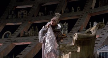 Movie still from “The Adventures of Baron Munchausen” (1988), directed by Terry Gilliam – A woman dressed in a costume holding a plate; Wide shot, Low angle