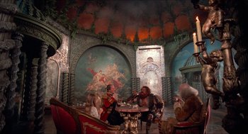 Movie still from “The Adventures of Baron Munchausen” (1988), directed by Terry Gilliam – A group of people sitting at a table in a room; Wide shot, High angle