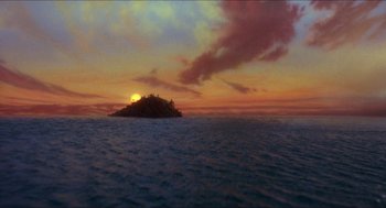 Movie still from “The Adventures of Baron Munchausen” (1988), directed by Terry Gilliam – The sun is setting over a small island in the middle of the ocean; Extreme Wide shot, High angle
