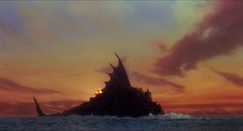 Movie still from “The Adventures of Baron Munchausen” (1988), directed by Terry Gilliam – The sun is setting over a small island in the ocean; Extreme Wide shot, Low angle