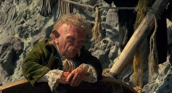 Movie still from “The Adventures of Baron Munchausen” (1988), directed by Terry Gilliam – An old man sitting on a boat in the water; Medium shot, High angle