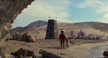 Movie still from “The Adventures of Baron Munchausen” (1988), directed by Terry Gilliam – A man dressed as a pirate walks on the beach; Extreme Wide shot, Low angle