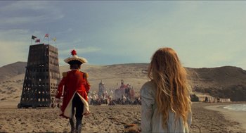Movie still from “The Adventures of Baron Munchausen” (1988), directed by Terry Gilliam – Two people are standing in the sand near a crowd of people; Extreme Wide shot, Low angle