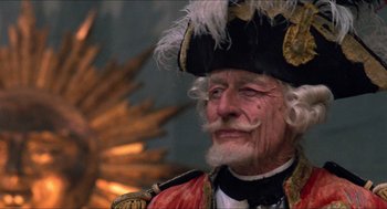 Movie still from “The Adventures of Baron Munchausen” (1988), directed by Terry Gilliam – An old man wearing a hat with feathers on it; Close Up shot, Low angle