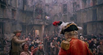 Movie still from “The Adventures of Baron Munchausen” (1988), directed by Terry Gilliam – A crowd of people gathered in an old building; Wide shot, Over the shoulder angle