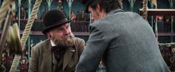 Movie still from “The Aeronauts” (2019), directed by Tom Harper – A man in a top hat and a man with a beard; Medium shot, Over the shoulder angle