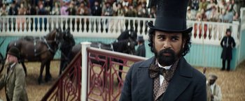 Movie still from “The Aeronauts” (2019), directed by Tom Harper – A man in a top hat and a bow tie standing in front of a crowd of onlookers; Medium shot, Over the shoulder angle