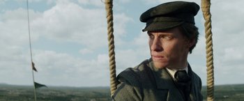 Movie still from “The Aeronauts” (2019), directed by Tom Harper – A man in a hat is holding a rope; Close Up shot, Low angle