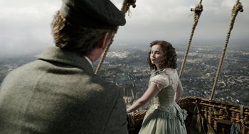 Movie still from “The Aeronauts” (2019), directed by Tom Harper – A man and a woman riding on the side of a swing; Medium shot, High angle