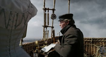 Movie still from “The Aeronauts” (2019), directed by Tom Harper – A man standing on top of a boat in the water; Medium shot, Low angle