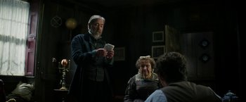Movie still from “The Aeronauts” (2019), directed by Tom Harper – An old man and woman in a dark room holding money; Medium shot, Over the shoulder angle