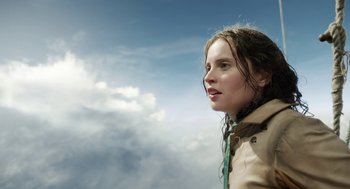 Movie still from “The Aeronauts” (2019), directed by Tom Harper – A young woman is standing in front of a cloudy sky; Close Up shot, Low angle