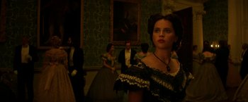 Movie still from “The Aeronauts” (2019), directed by Tom Harper – A woman standing in front of a group of people in a room; Close Up shot, Over the shoulder angle