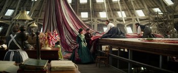 Movie still from “The Aeronauts” (2019), directed by Tom Harper – A group of people sitting on top of a wooden platform; Wide shot, Low angle