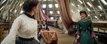 Movie still from “The Aeronauts” (2019), directed by Tom Harper – A man and a woman sitting at a table in front of curtains; Wide shot, Over the shoulder angle