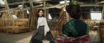 Movie still from “The Aeronauts” (2019), directed by Tom Harper – A woman in white shirt and black skirt standing next to another woman; Medium shot, Over the shoulder angle